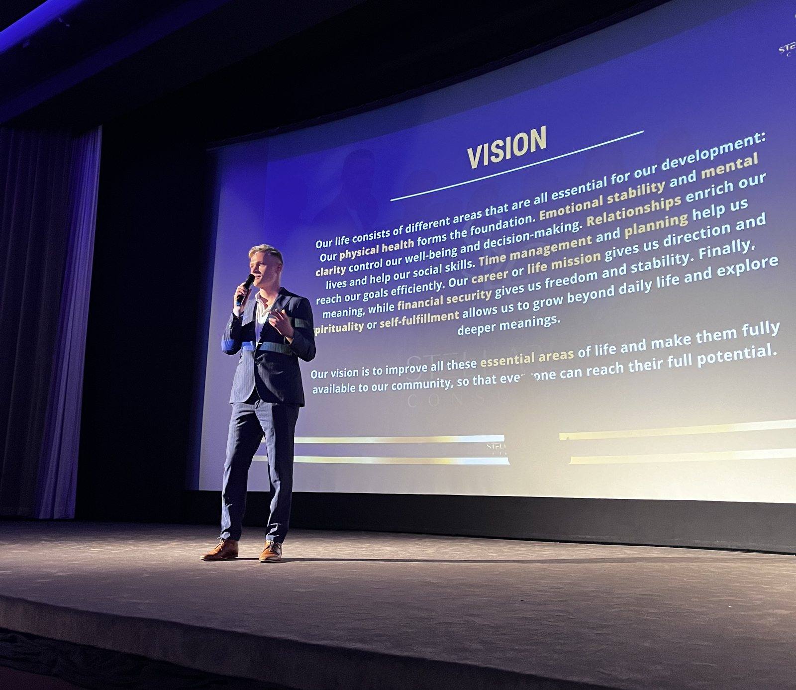 Niklas spricht auf einer Bühne vor einer großen Leinwand mit der Überschrift Vision.