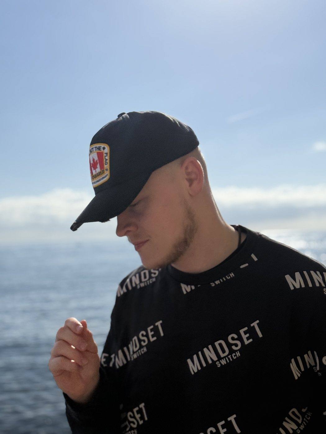 Niklas mit Kappe am Meer, den Blick gesenkt, im Hintergrund der Horizont.